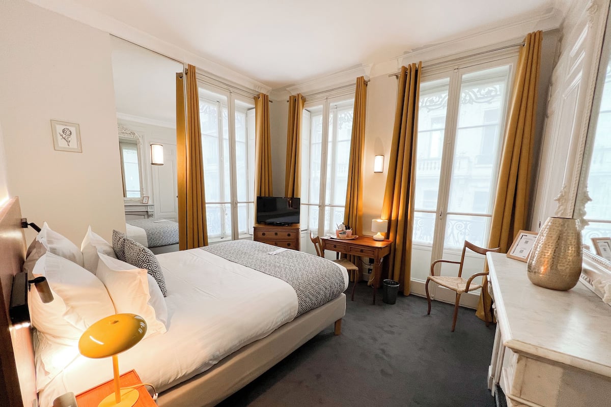 A hotel room with a bed, a desk, a chair, a television, and a lamp.