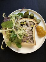 Un piatto con un involtino di carne, sottaceti e un'insalata.