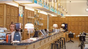 Una zona de bar con armarios de madera, encimera de mármol y lámparas colgantes.