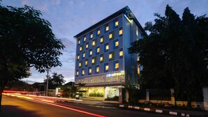 Un hotel con fachada moderna, varios pisos y una entrada bien iluminada.