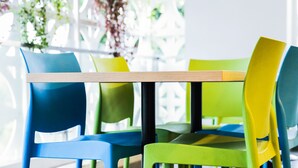 Una mesa con sillas en una habitación con ventanas amplias y plantas.