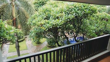 Un balcón con vista a un jardín con diversas plantas y una palmera.