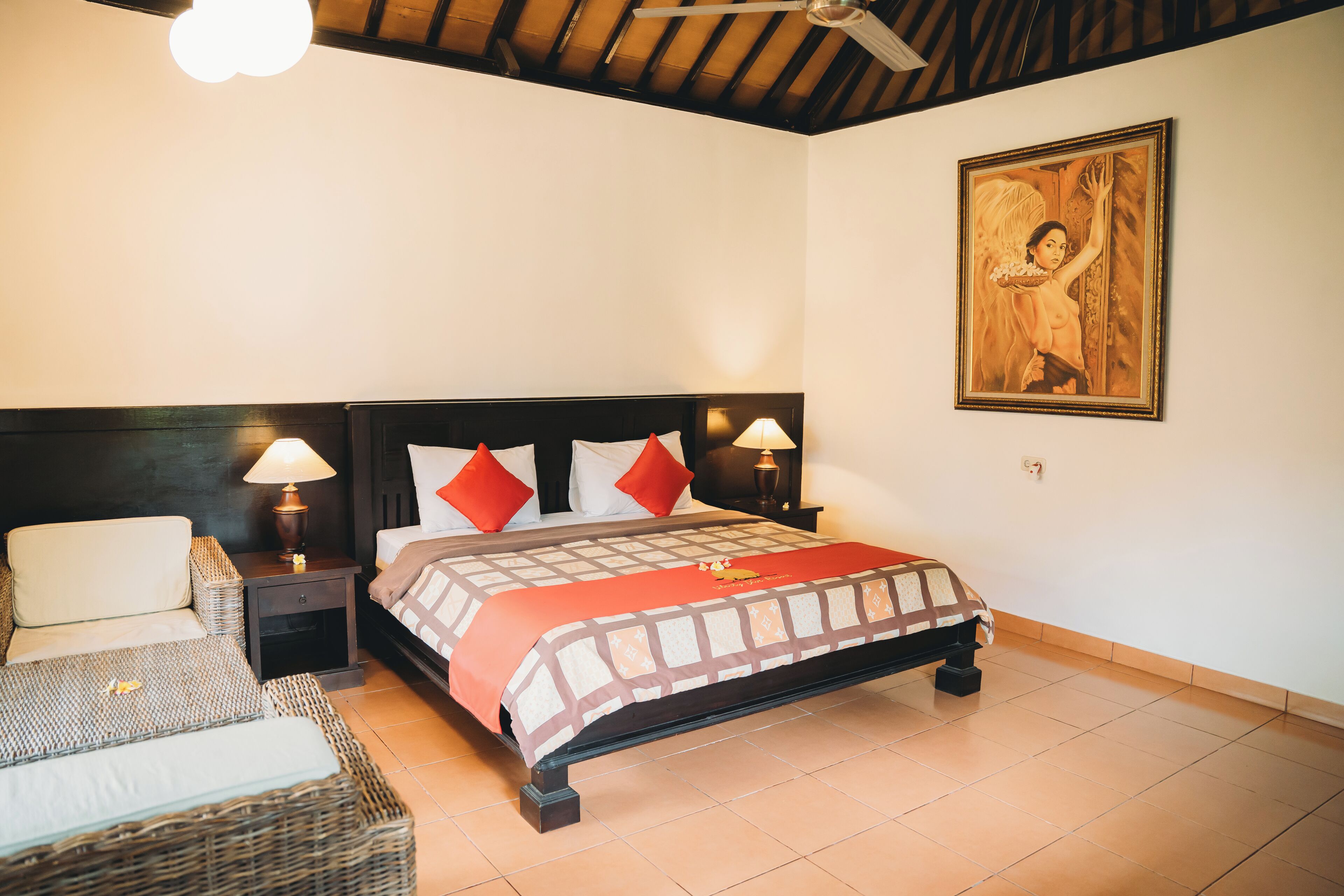 Un dormitorio con cama, mesitas de noche, lámpara, un cuadro y ventilador de techo.