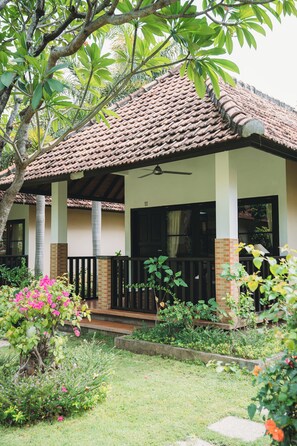 A house with a tiled roof, a balcony, and a garden with various plants and flowers. - Liberty Dive Resort (Tulamben)