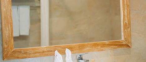 A bathroom with a white sink, a wooden-framed mirror, and a towel hanging on a rack.