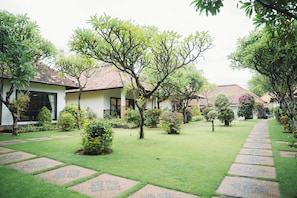 A courtyard with a paved walkway, surrounded by lush greenery and small trees. - Liberty Dive Resort (Tulamben)
