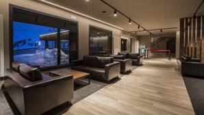 Eine moderne Lobby mit Ledersofas, einem Holztisch und großen Fenstern mit Blick auf eine verschneite Landschaft.