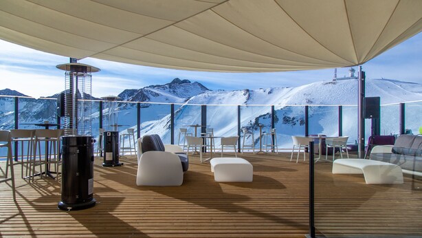 Eine Terrasse mit Sitzgelegenheit und Blick auf schneebedeckte Berge.