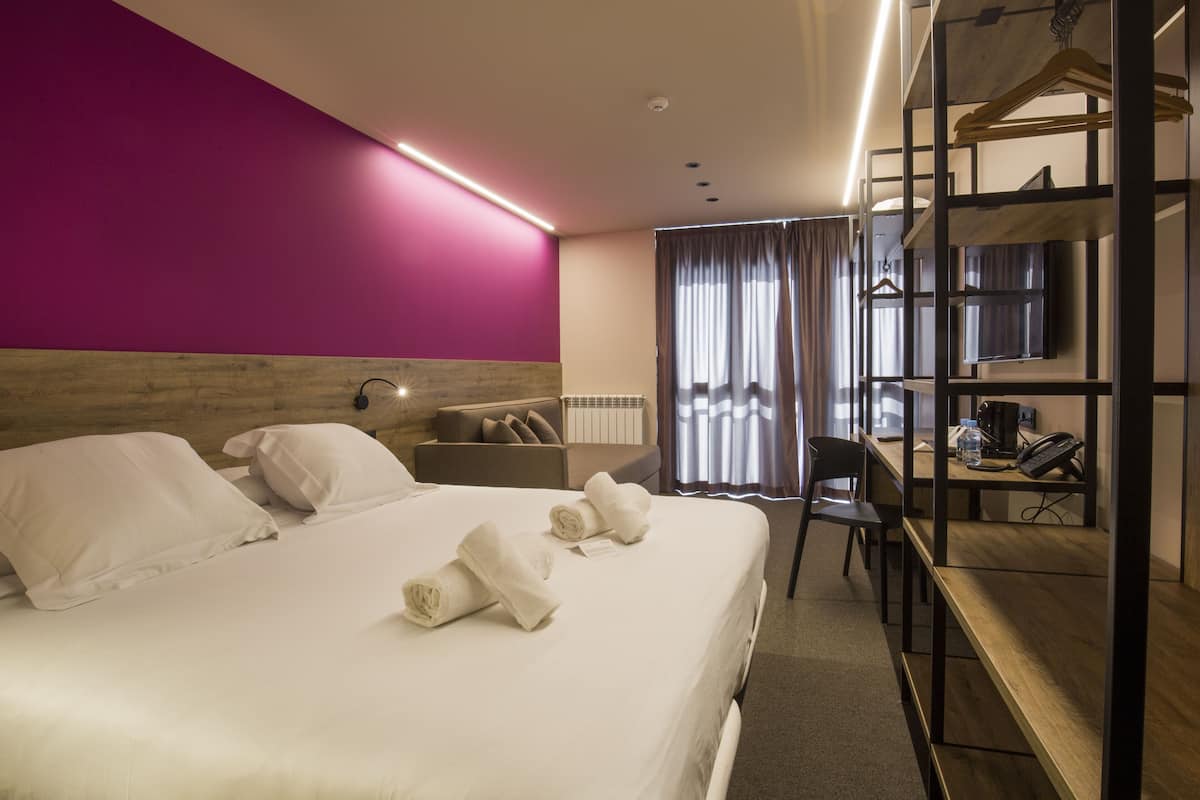 Une chambre d’hôtel avec un grand lit, un bureau, une chaise, une télévision et une armoire.