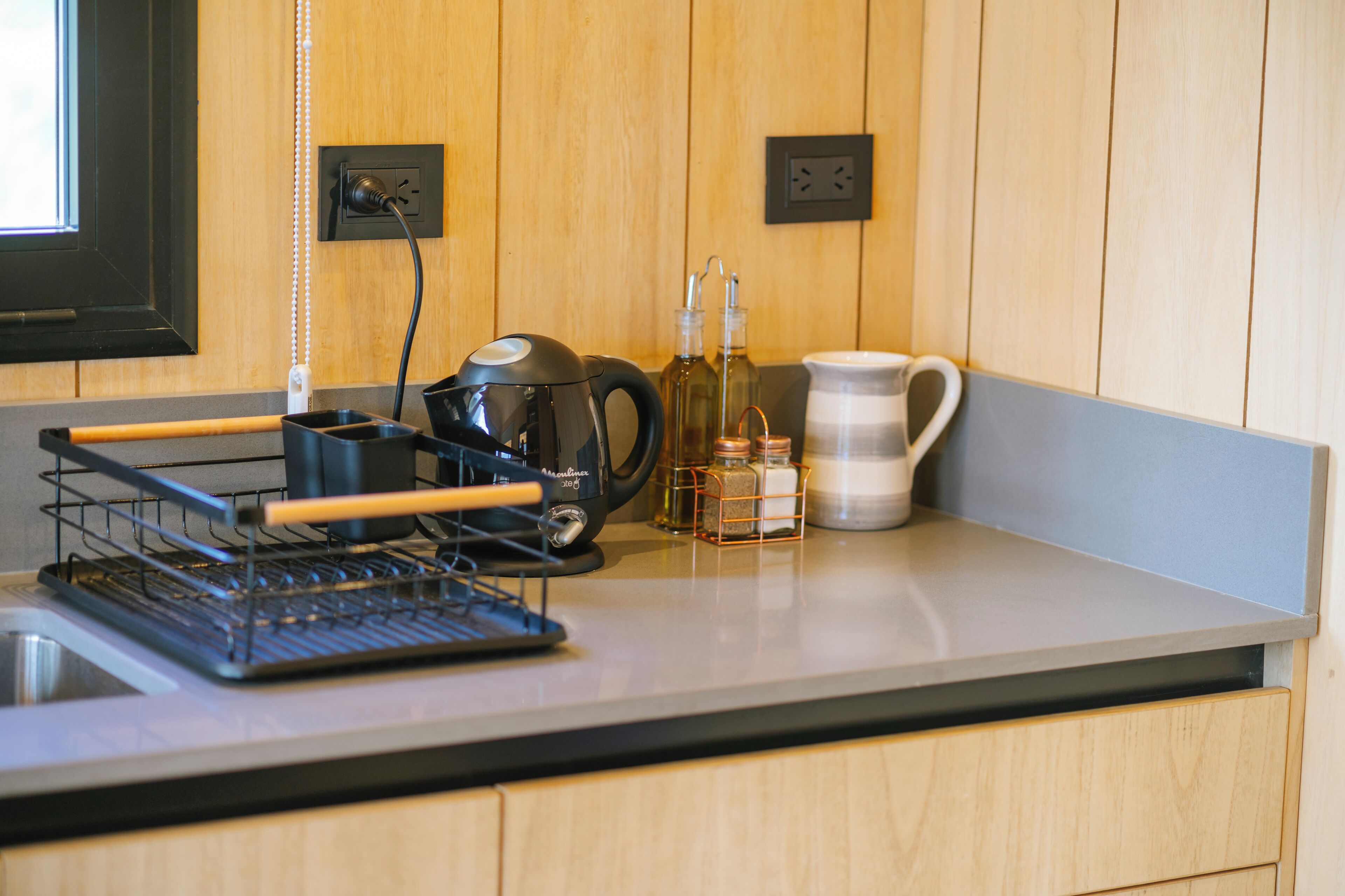 A kitchen with a coffee maker, a kettle, and a spice rack.