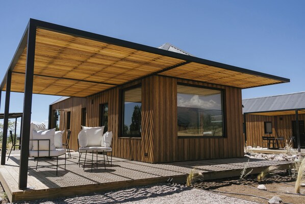 A modern wooden cabin with a covered patio, large windows, and outdoor seating. - La Morada Lodge - Valle de Uco (Tunuyan)