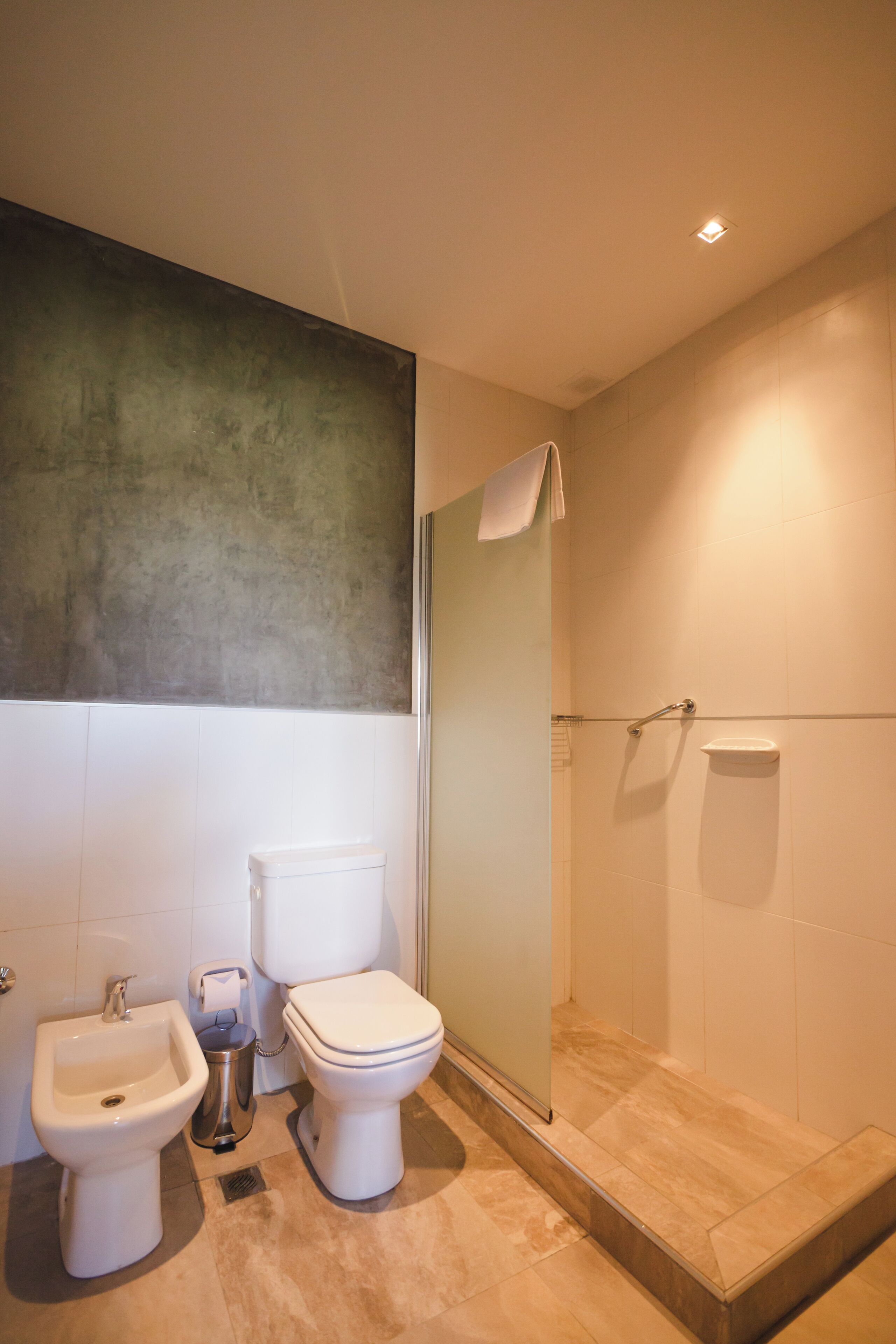 A modern bathroom with a bidet, toilet, and shower.