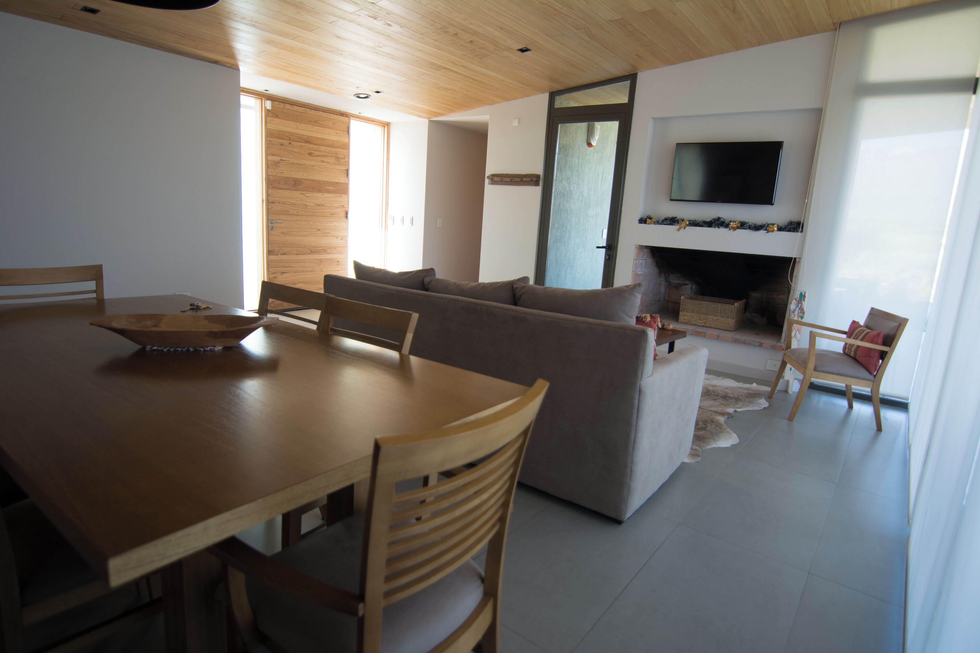 A modern living room with a wooden dining table, sofas, and a fireplace.