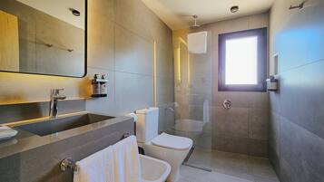 A modern bathroom with a large mirror, a sink, a toilet, and a shower enclosure.