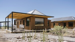 A modern building with a wooden exterior, large windows, and a covered patio area with outdoor seating. - La Morada Lodge - Valle de Uco (Tunuyan)
