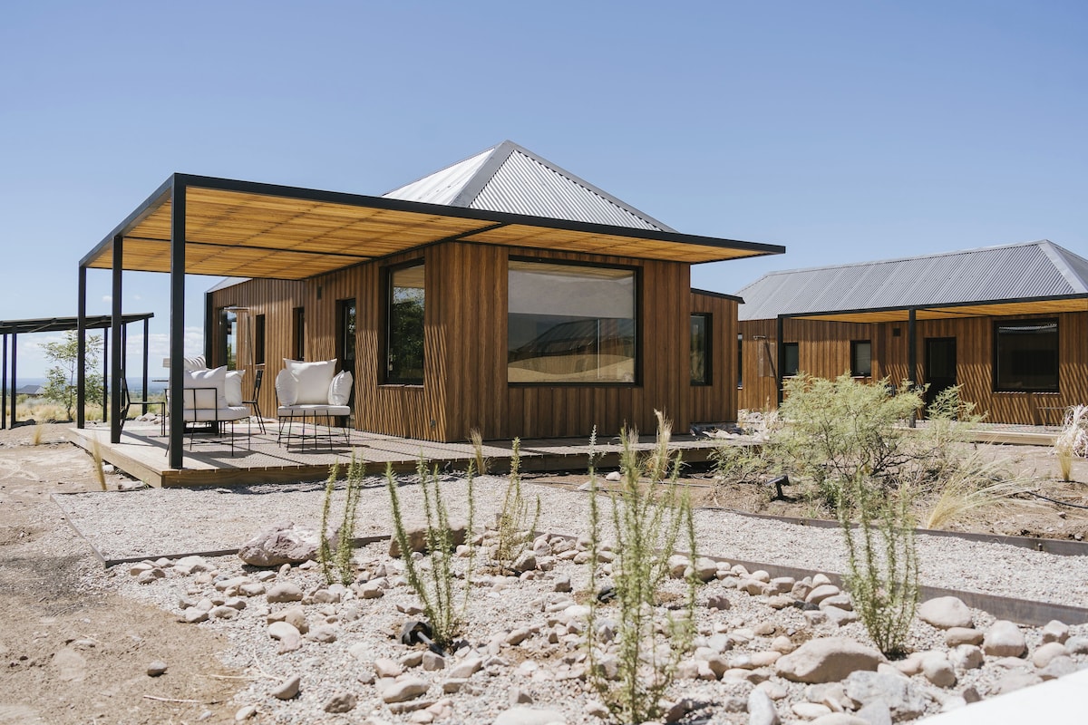 A modern building with a wooden exterior, large windows, and a covered patio area with outdoor seating.