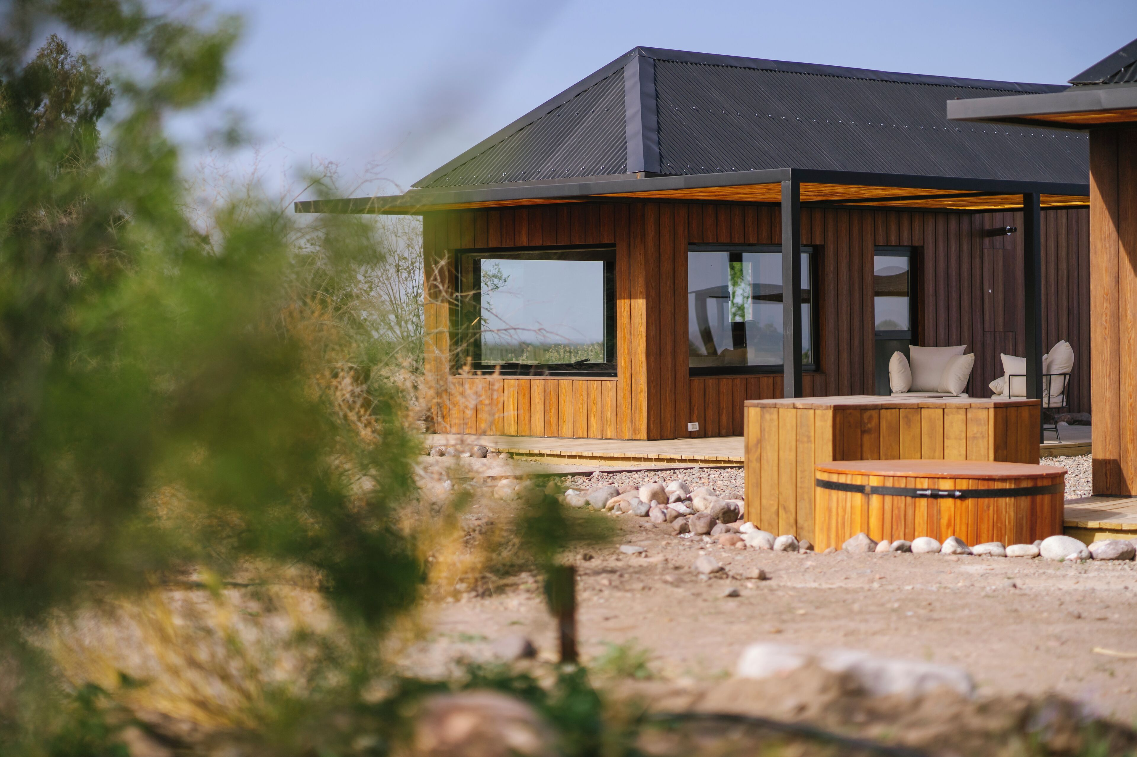 Una casa moderna con amplios ventanales, fachada de madera y un patio con jacuzzi.