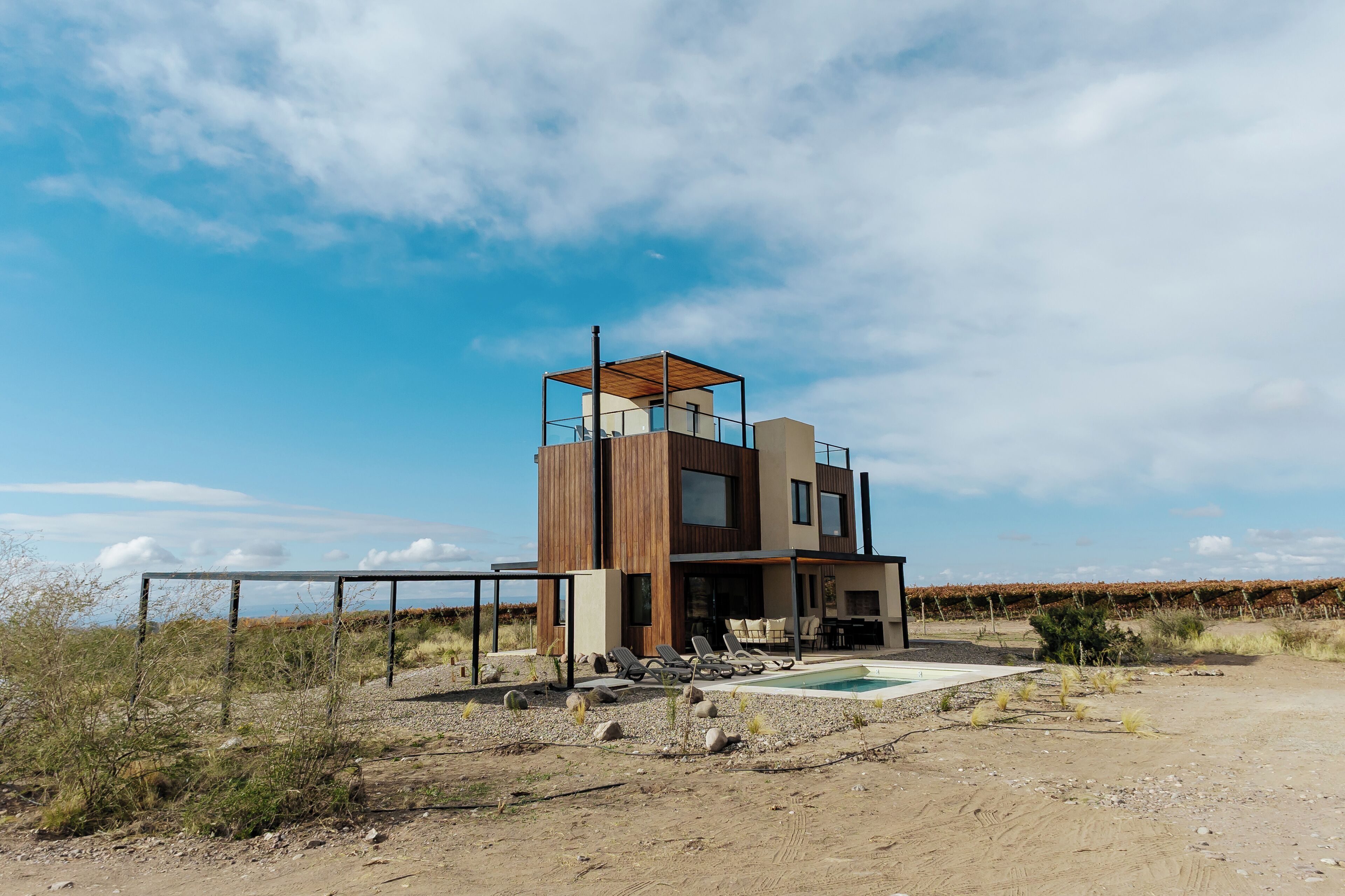 A modern two-story house with a pool, surrounded by a natural landscape.