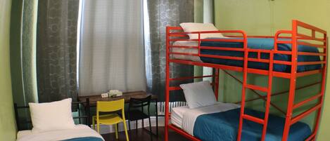 Habitación con literas, un escritorio, una silla, una ventana con cortinas y un radiador.