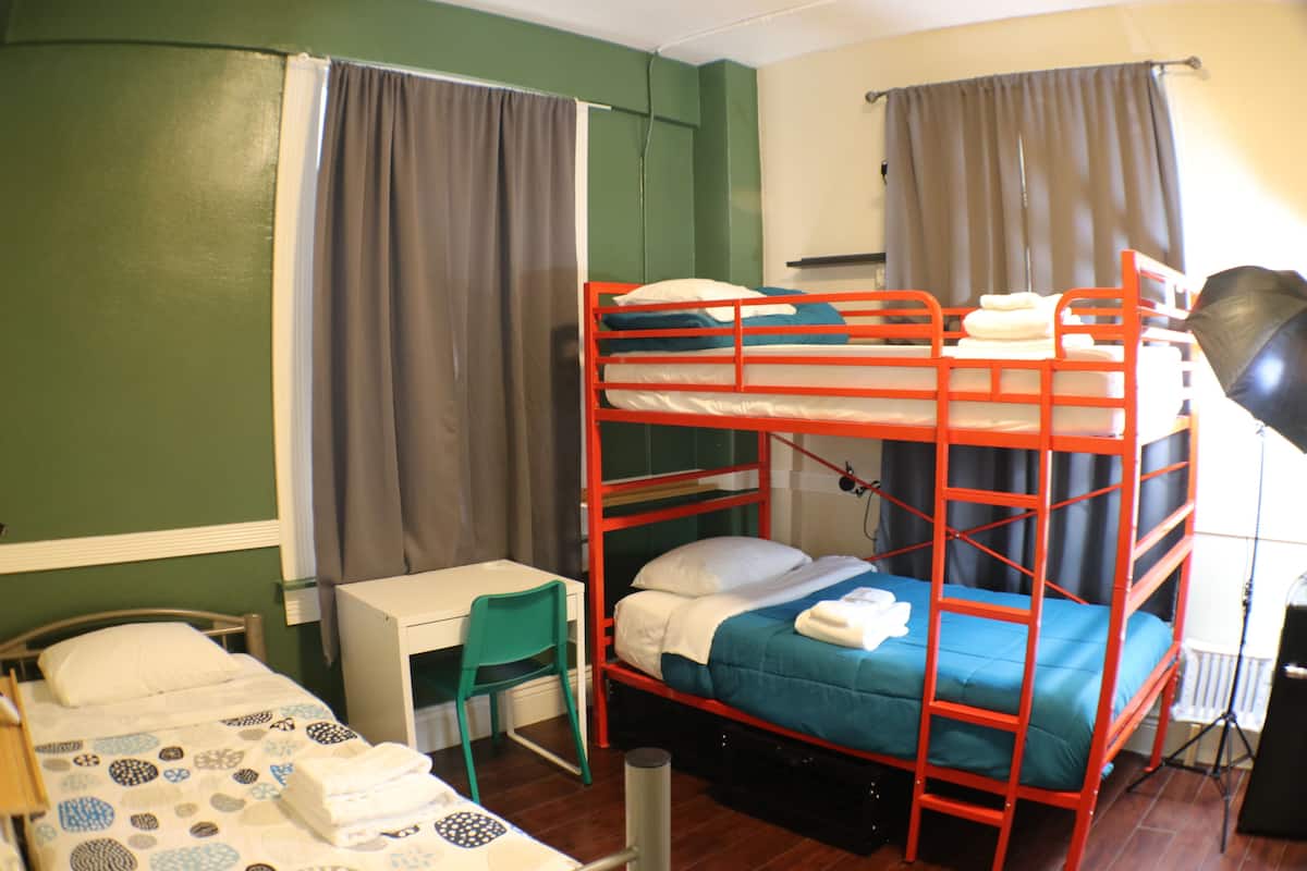 A bunk bed with a desk and chair, a small table, and a lamp.