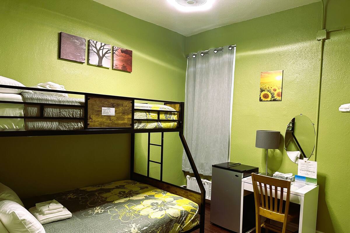 A bunk bed with a desk and chair, a radiator, and a window with curtains.