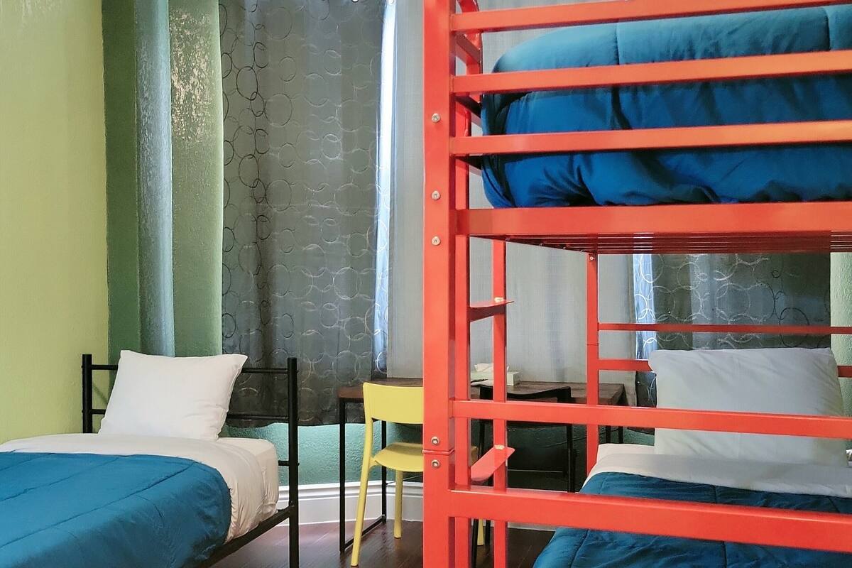A dormitory room with bunk beds, a desk, and a chair.