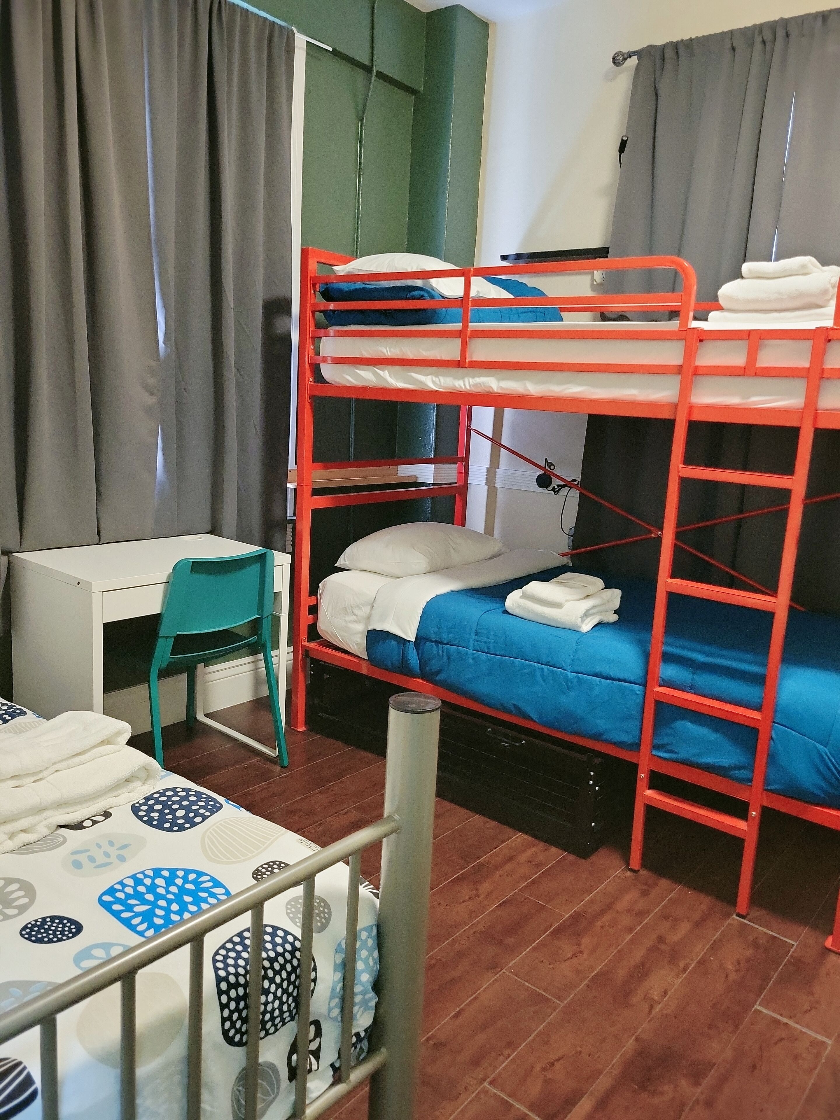 A bunk bed room with a desk and chair, grey curtains, and a patterned floor.