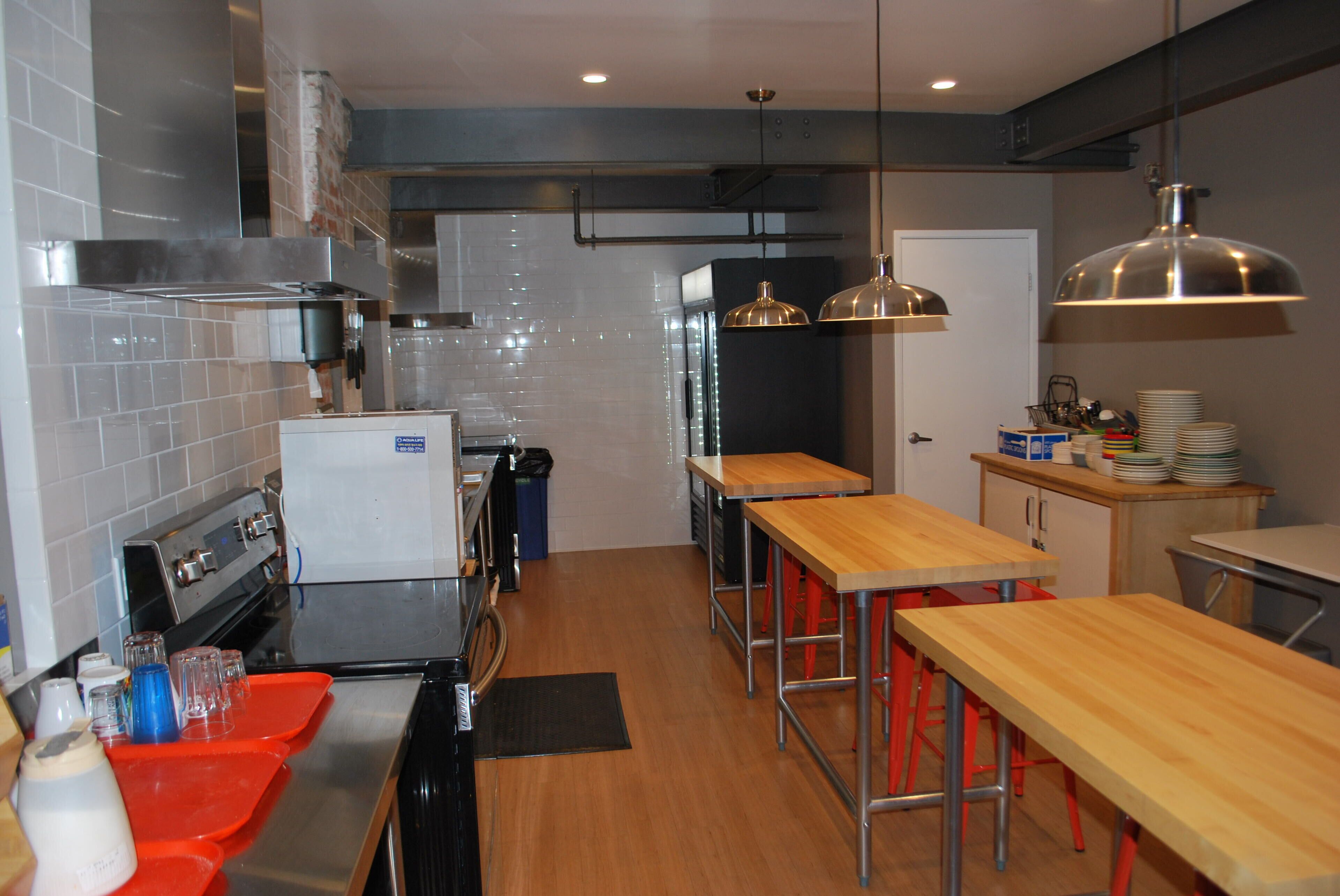 Una cocina moderna con electrodomésticos de acero inoxidable, mesas de madera y taburetes rojos.