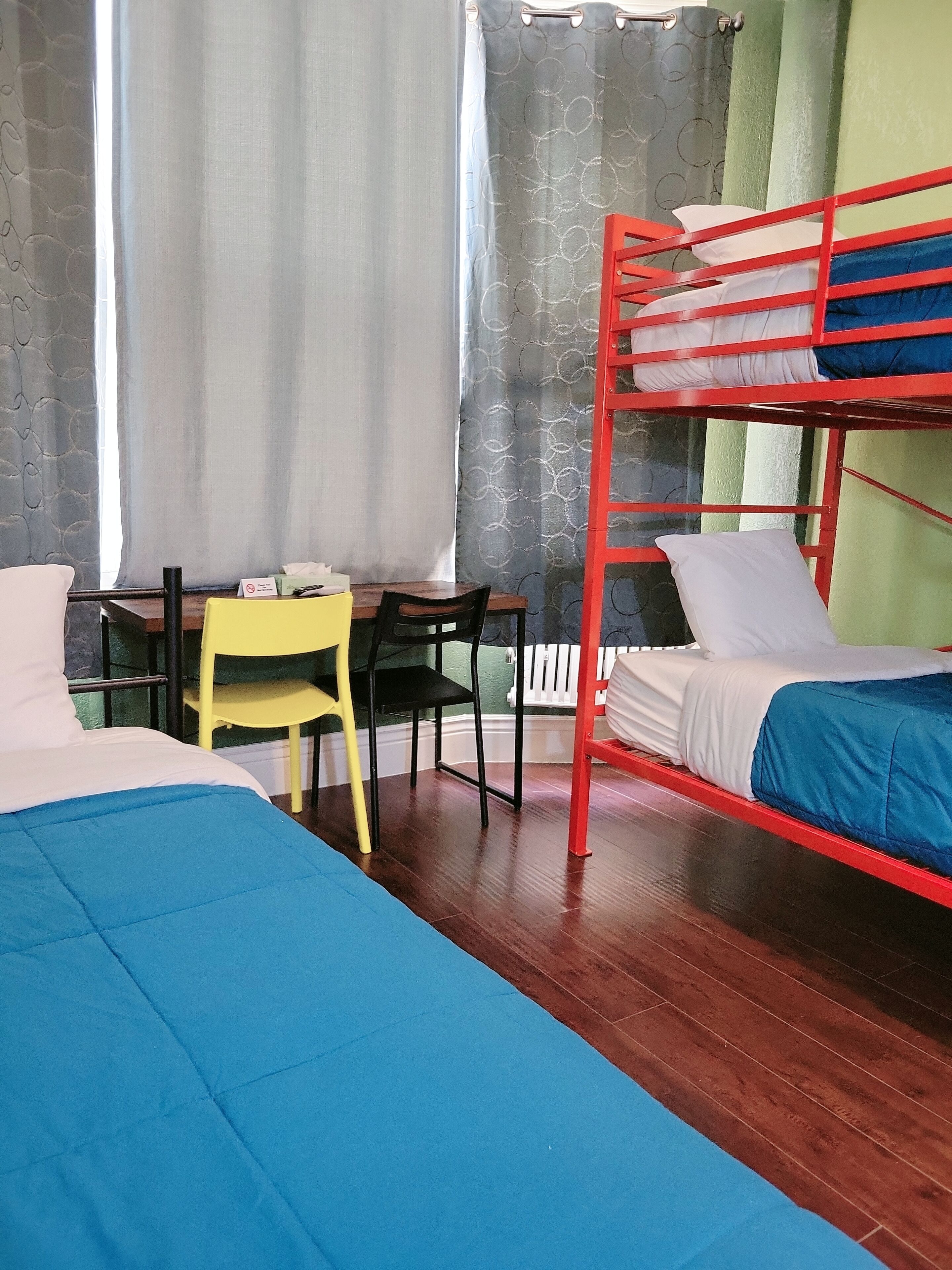 Um quarto com beliches, escrivaninha, cadeira e uma cama.