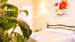 Una habitación de hotel con una cama, una mesita de noche, una lámpara de pared y un cuadro de flores.