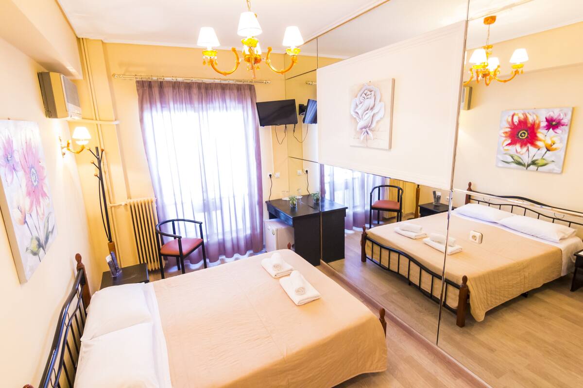 Ein Hotelzimmer mit zwei Betten, einem Schreibtisch, einem Sessel, einem Fernseher und Bildern an der Wand.