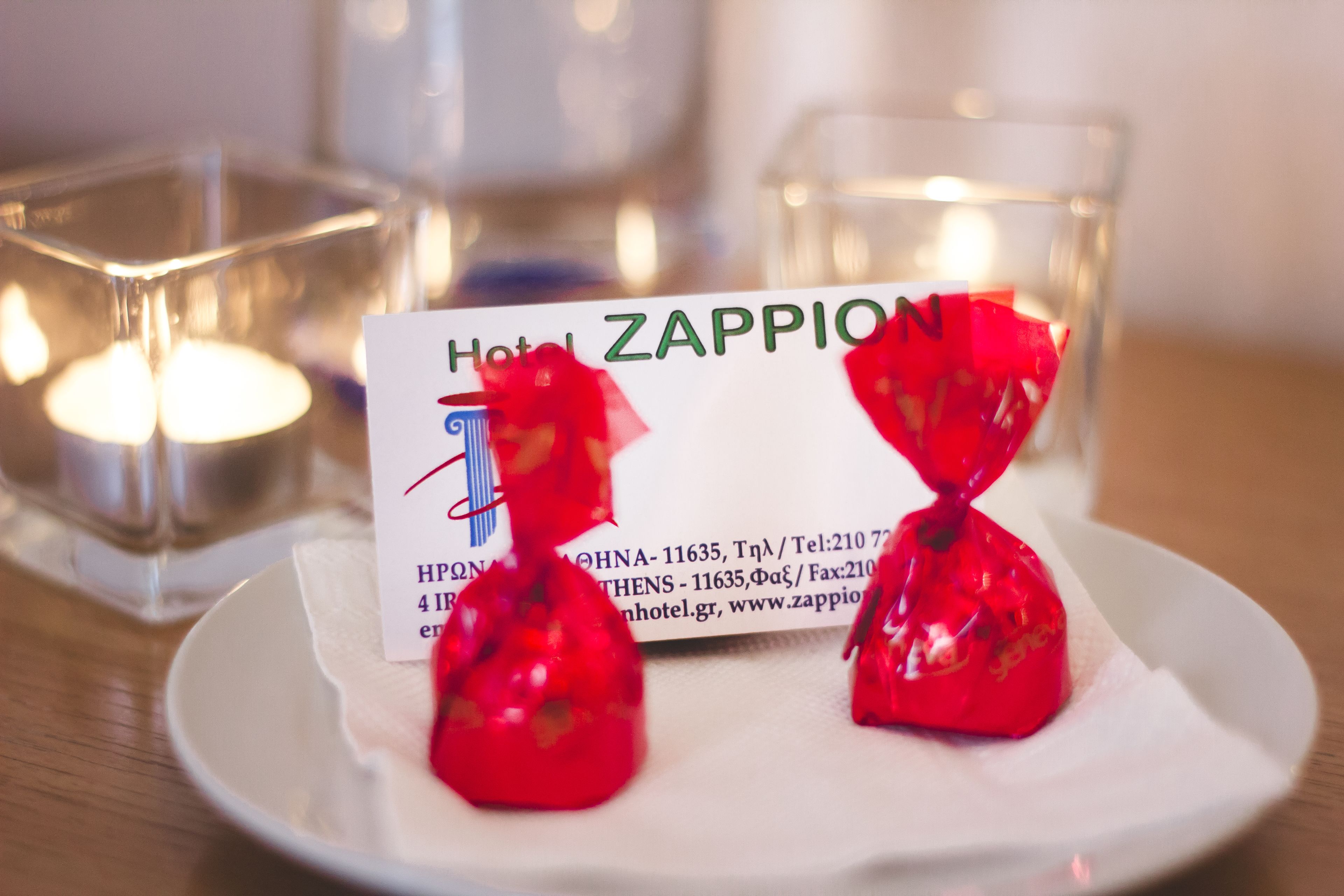 A hotel business card with contact details and two red gift bags on a white plate.