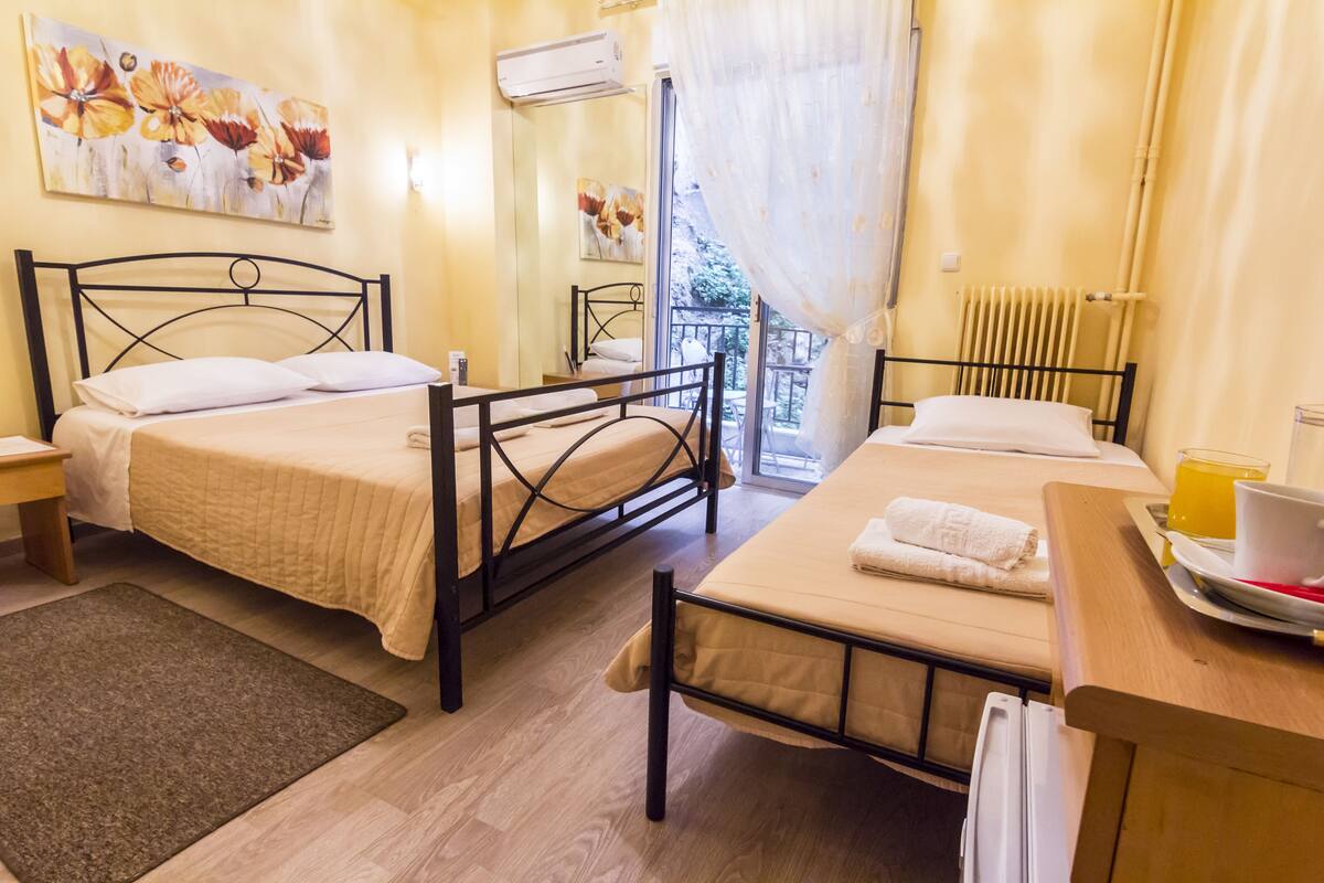 Ein Hotelzimmer mit zwei Betten, Holzboden, einem Fenster mit Vorhängen und einer Heizung.