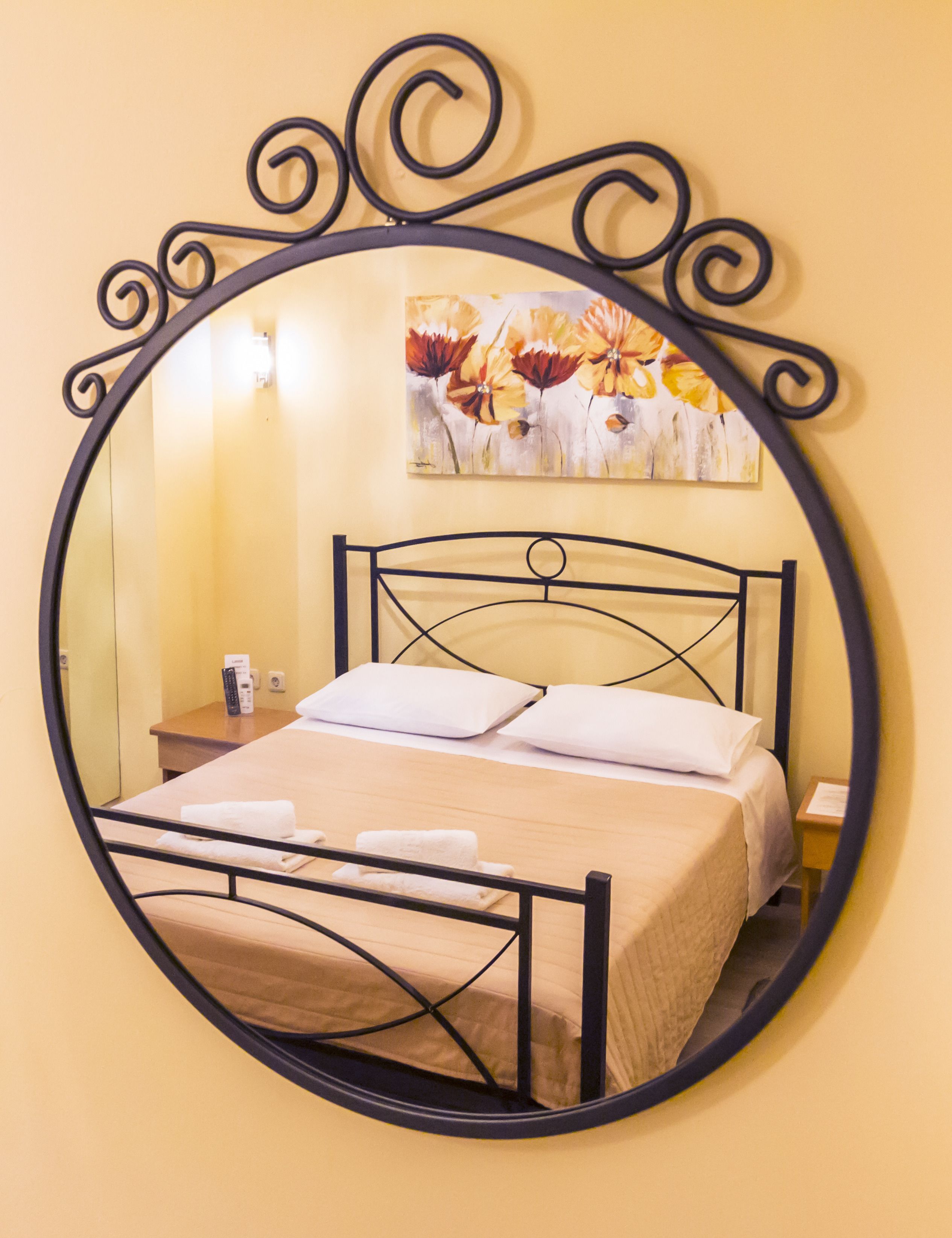 A bed with a headboard, a nightstand, a lamp, and a painting on the wall.