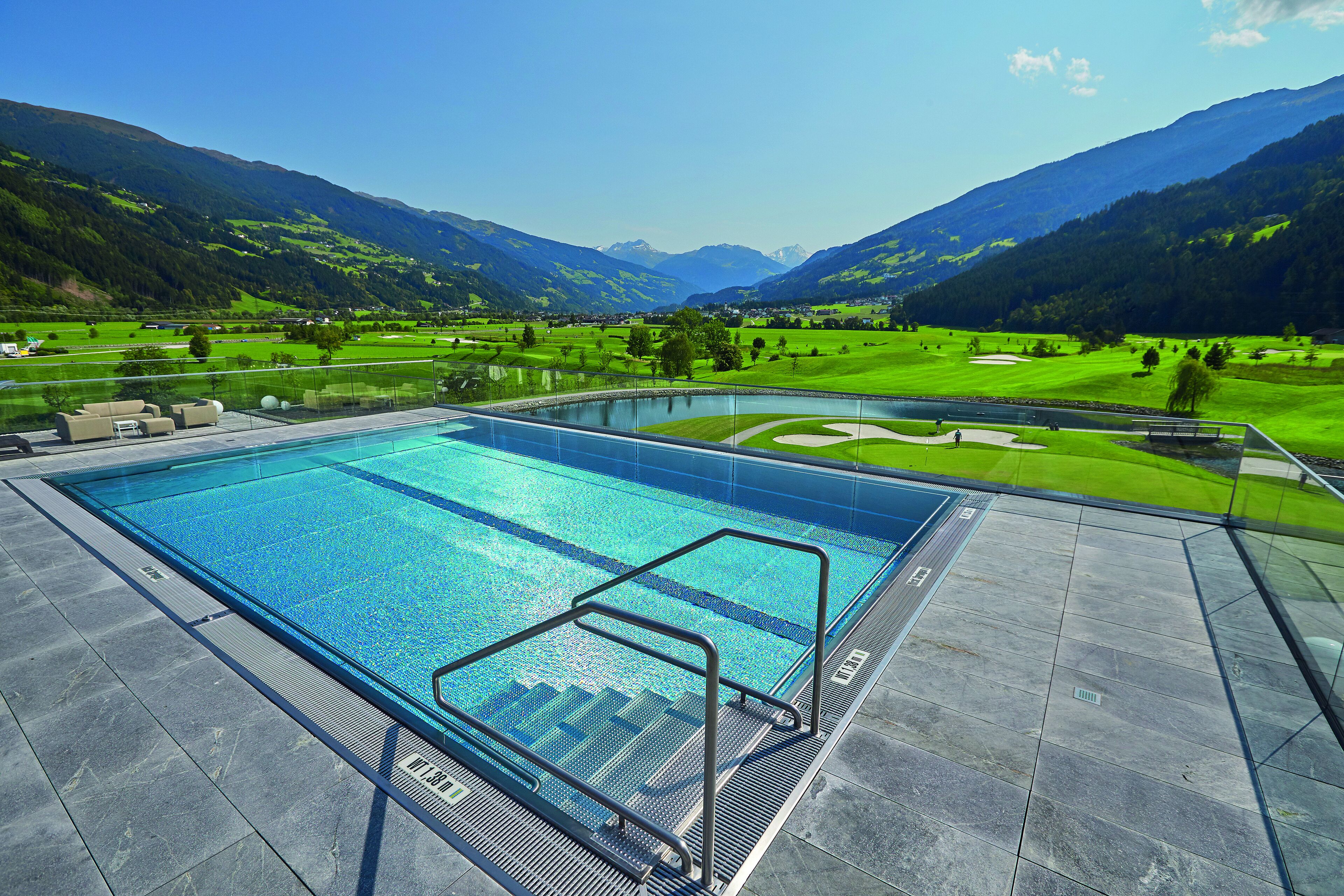 A swimming pool with a view of mountains and a golf course.