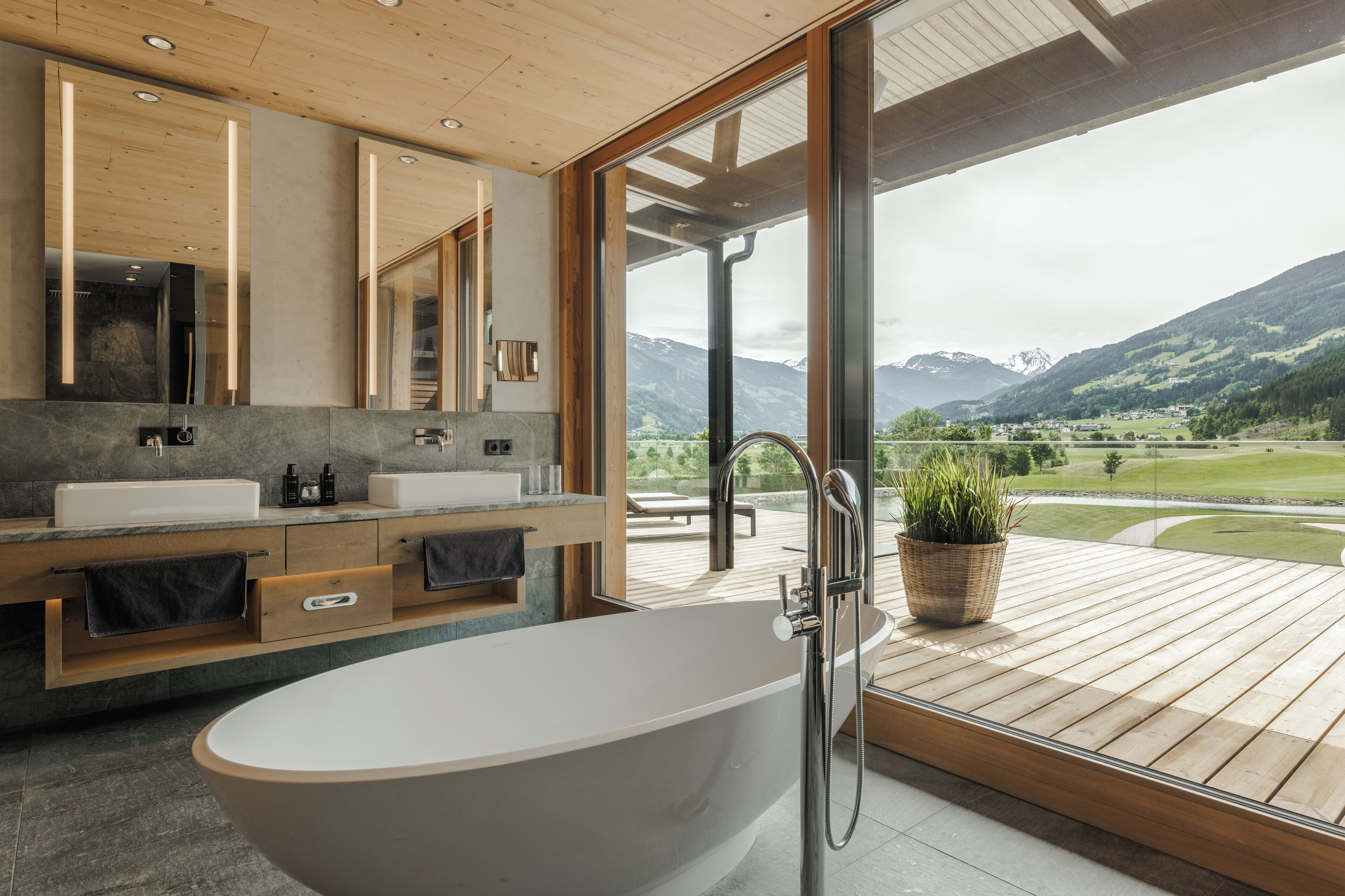 Un baño moderno con una bañera independiente, lavamanos dobles y un espejo grande.