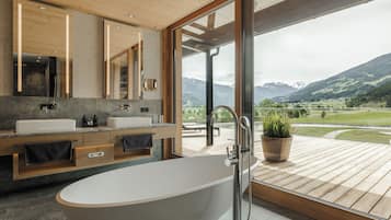 Un baño moderno con una bañera independiente, lavamanos dobles y un espejo grande.