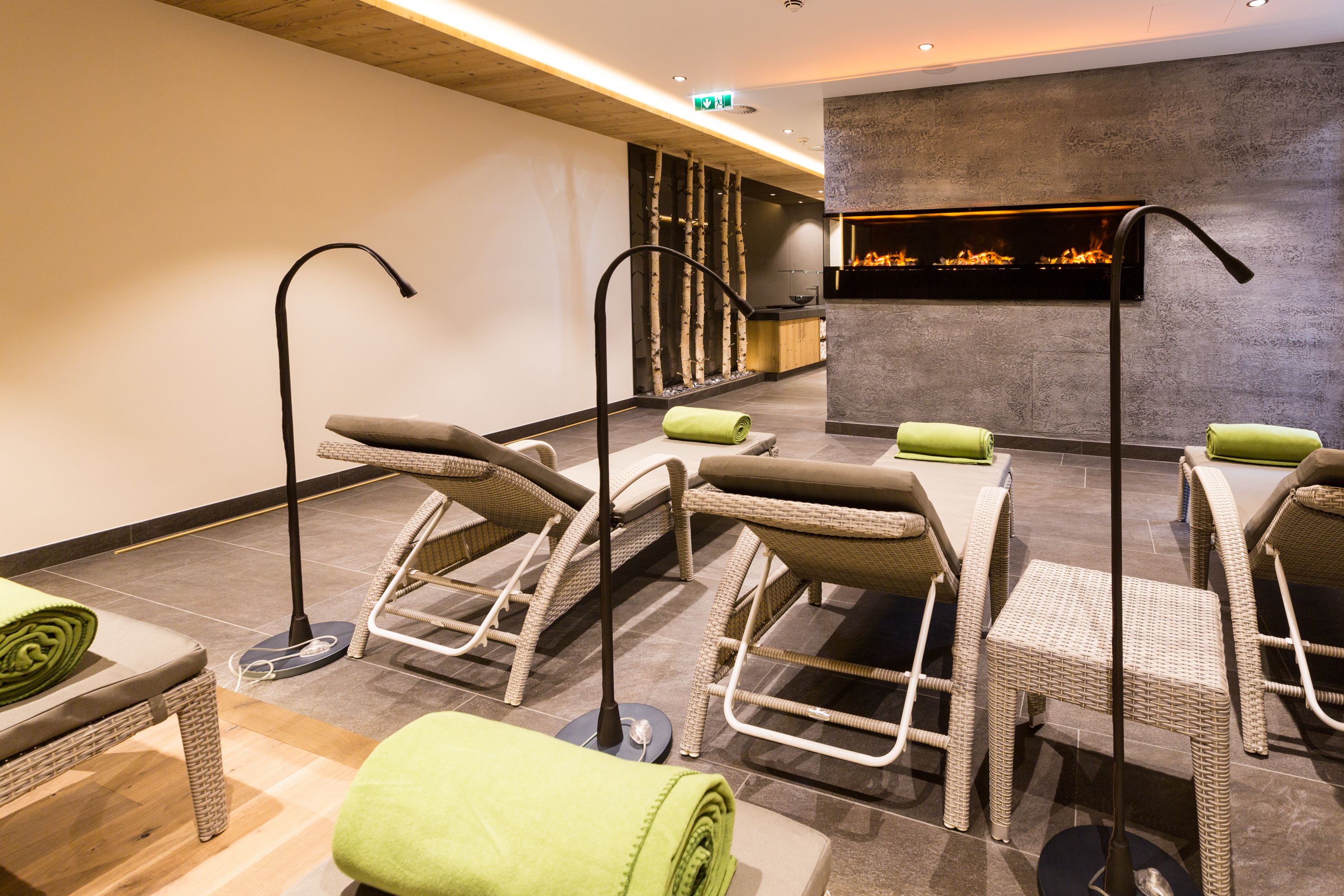 A spa area with wicker chairs and a massage table, a fire feature, and a reception desk.