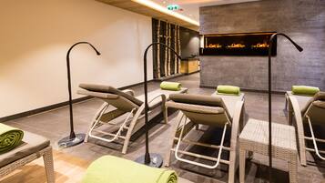 A spa area with wicker chairs and a massage table, a fire feature, and a reception desk.