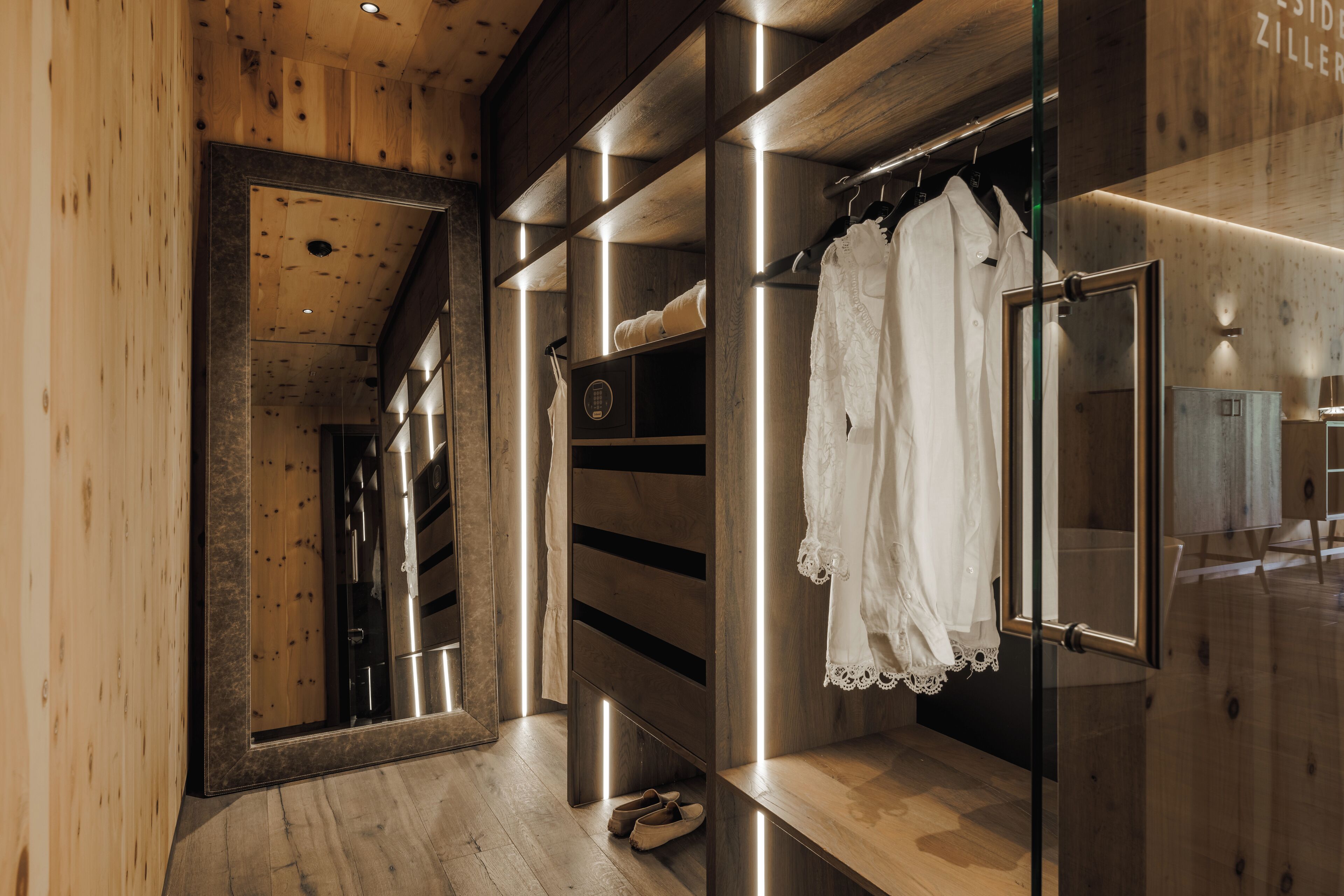 Un intérieur en bois avec une armoire en verre, un miroir et un porte-manteau mural.