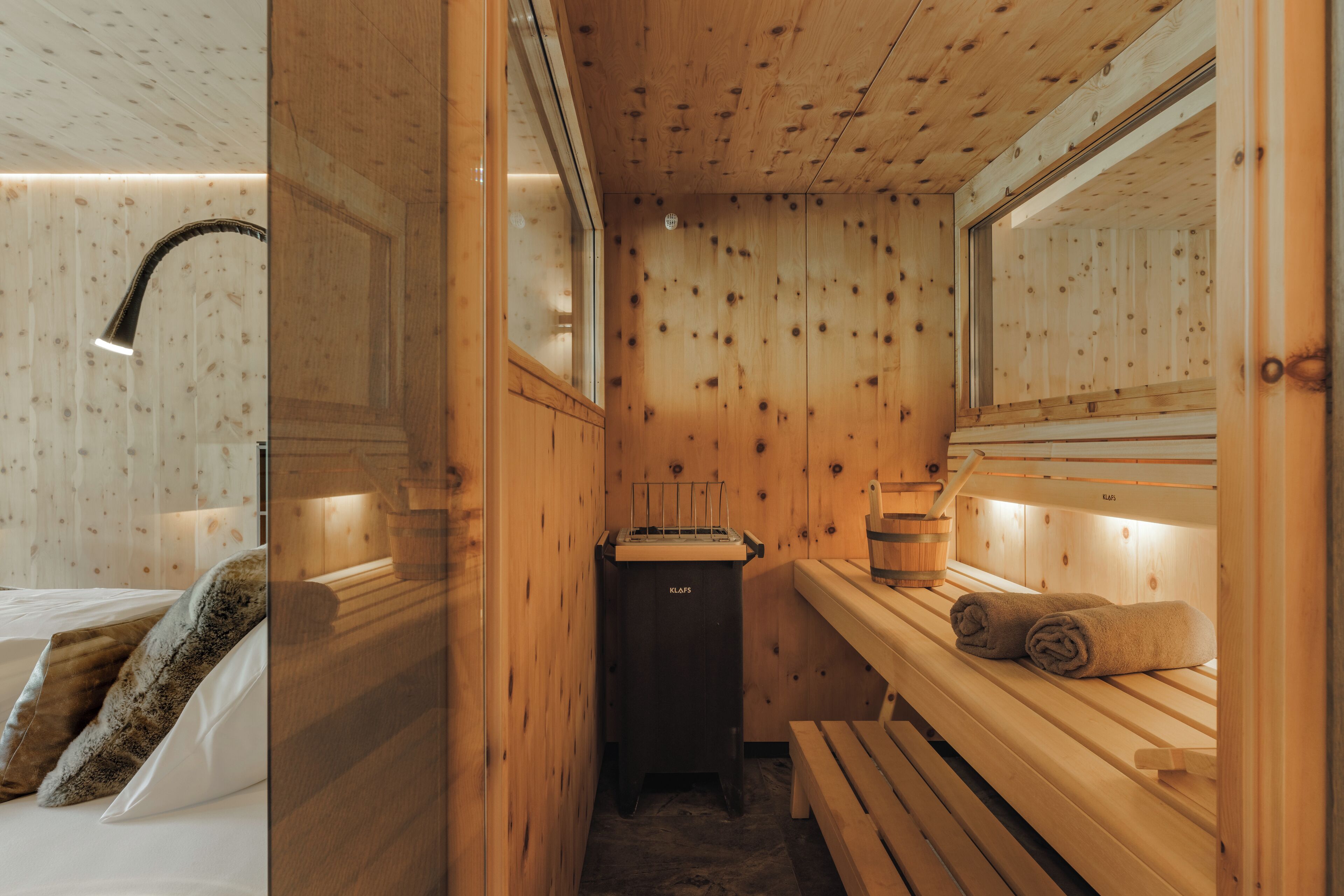 Ein Holzblockhaus-Interieur mit Bett, Bank, Sauna und Spiegel.