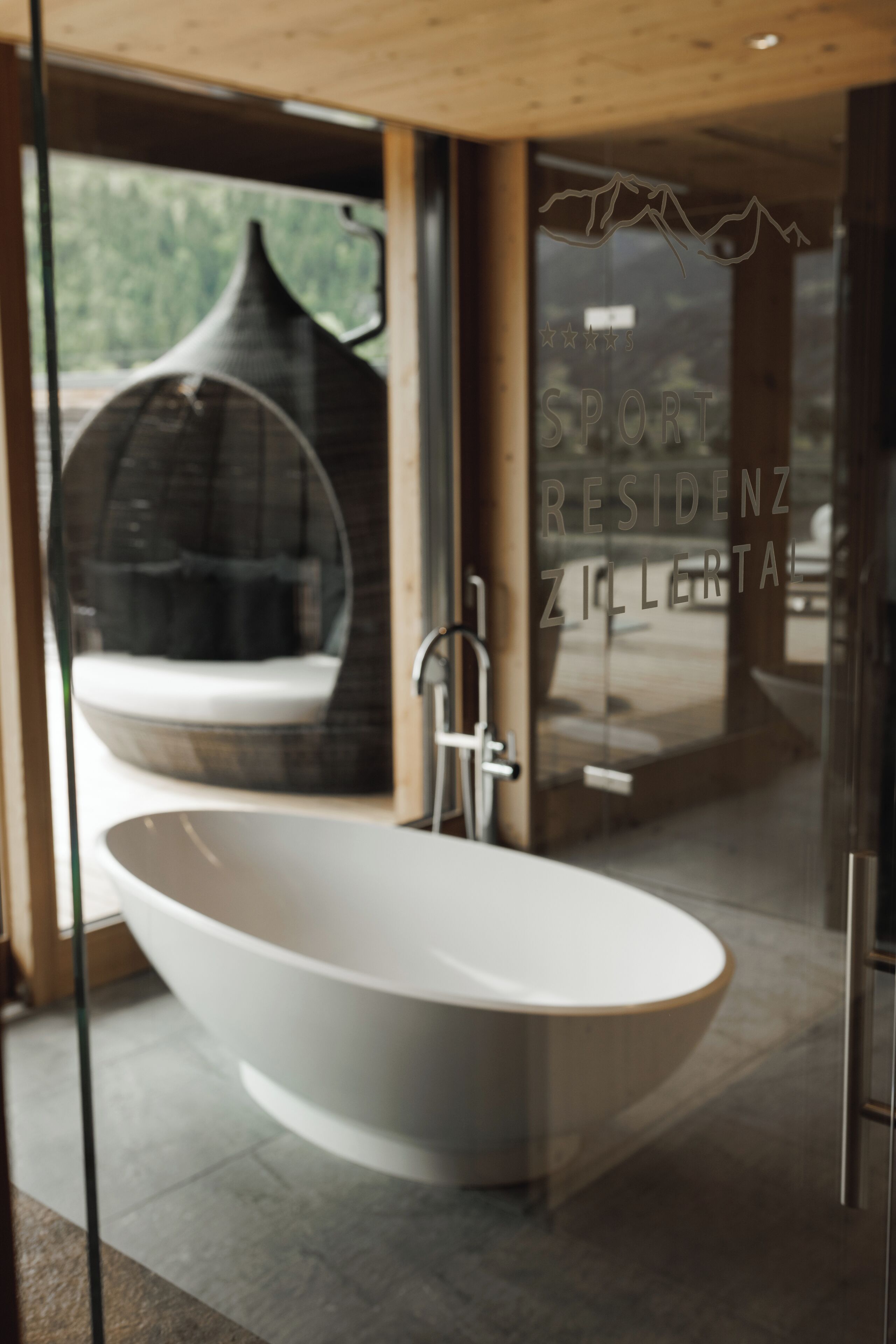 Un baño moderno con una bañera independiente, un box de ducha de vidrio y vistas a un paisaje montañoso a través de grandes ventanales.