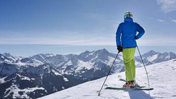A person skiing on a snowy mountain with a clear view of snow-covered peaks in the background.