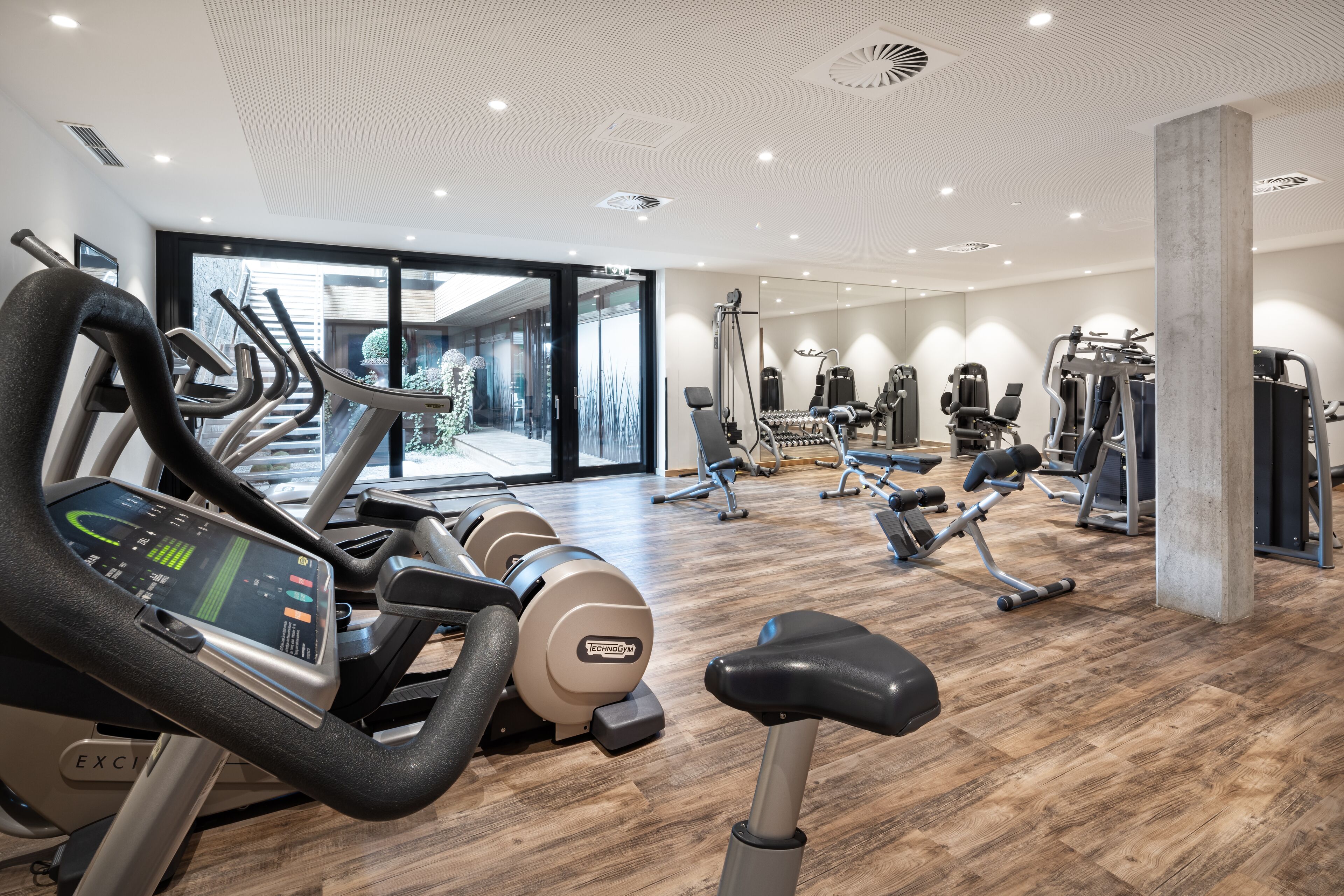 A modern gym with treadmills, weight machines, and a large mirror.