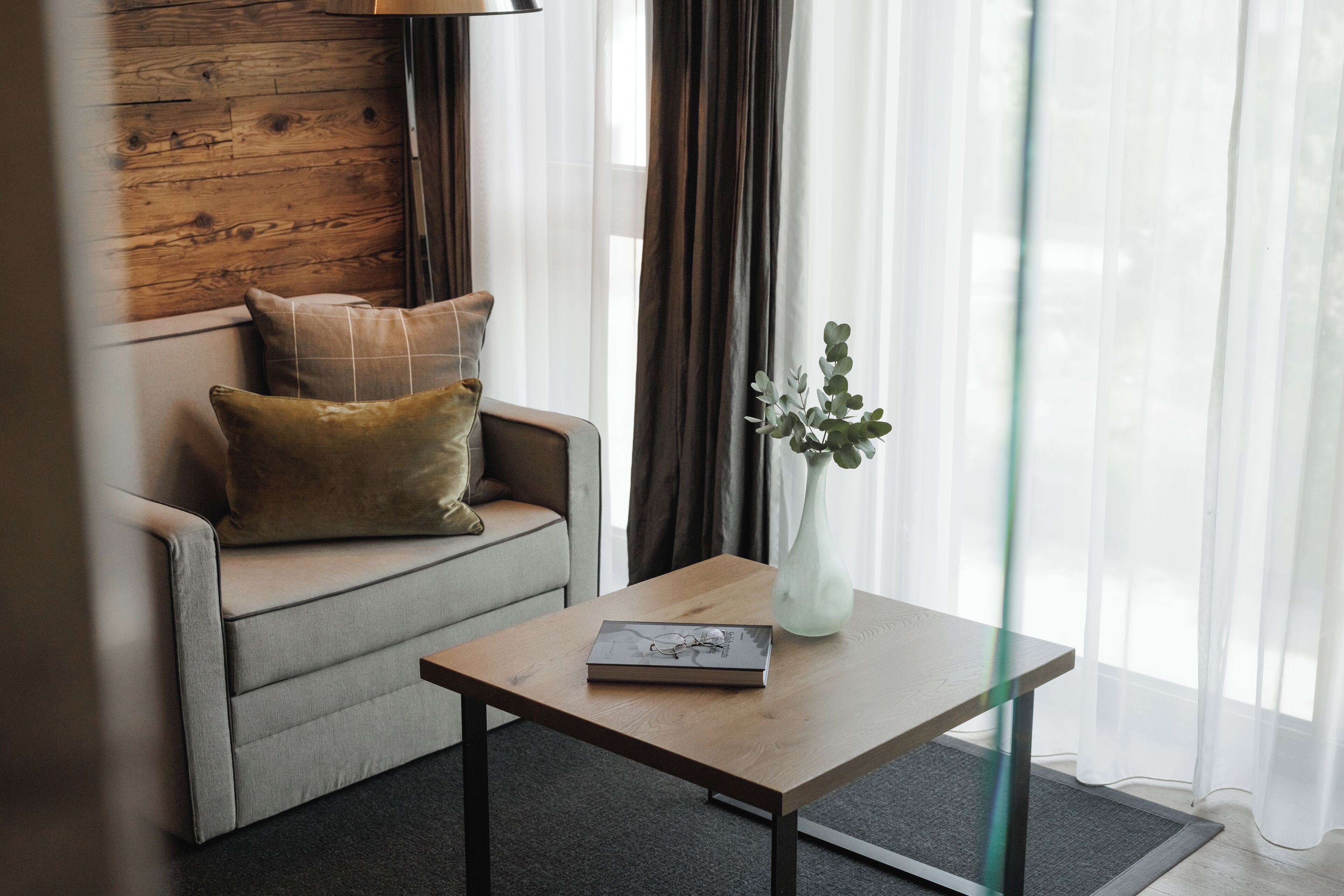 A modern living room with a sofa, a coffee table, and a vase with plants.