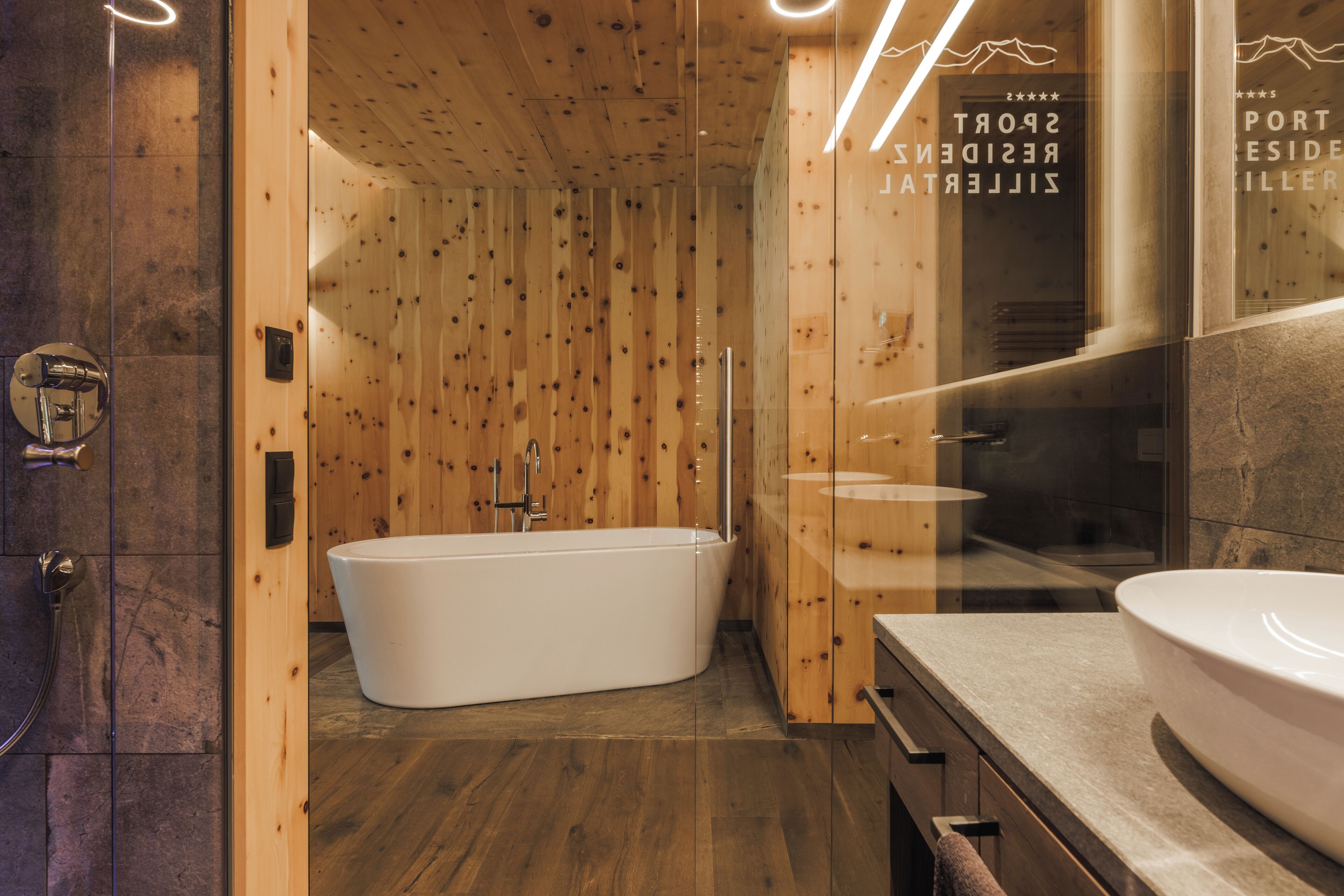 Une salle de bain moderne avec un intérieur en bois, une baignoire sur pieds et un grand lavabo.