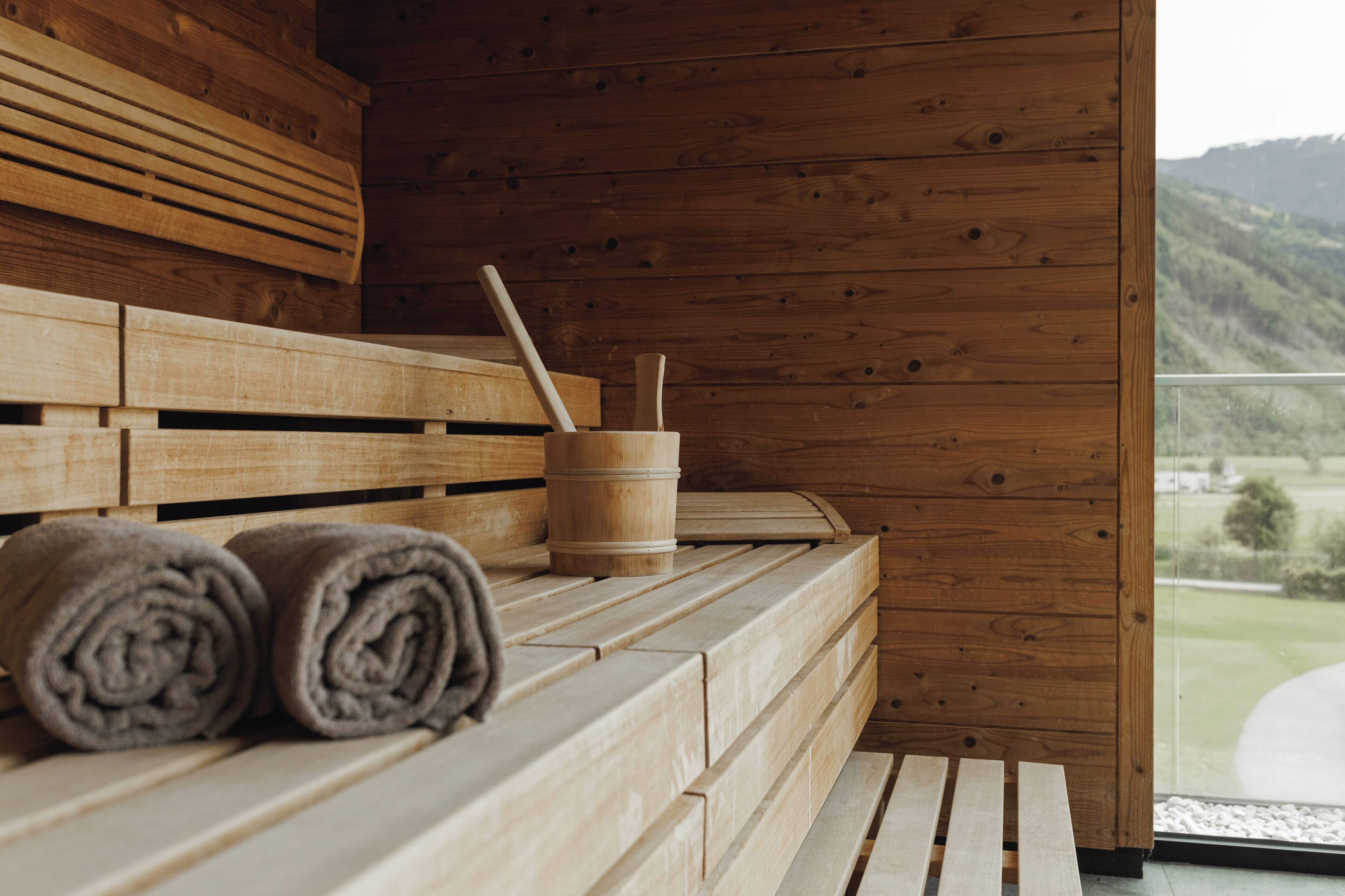 A wooden sauna with benches and a wooden bucket with a wooden stick.