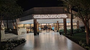 Exterior do Ghazala Beach Hotel com design moderno, amplas janelas de vidro e entrada bem iluminada.