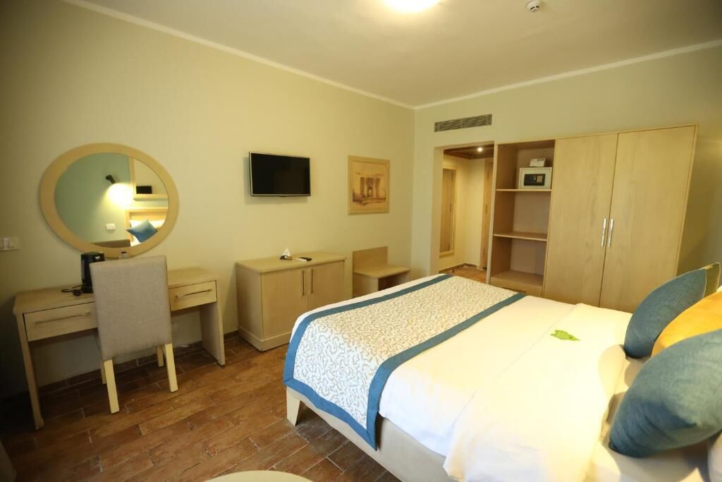 Een slaapkamer met een bed, een bureau, een stoel, een kledingkast en een televisie.