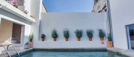 Een buitenzwembad, ligstoelen bij het zwembad